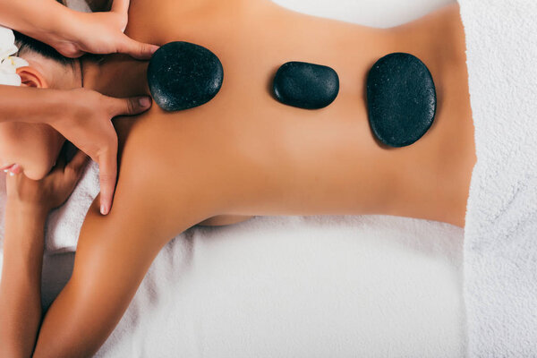 young woman having stone therapy at massage salon 