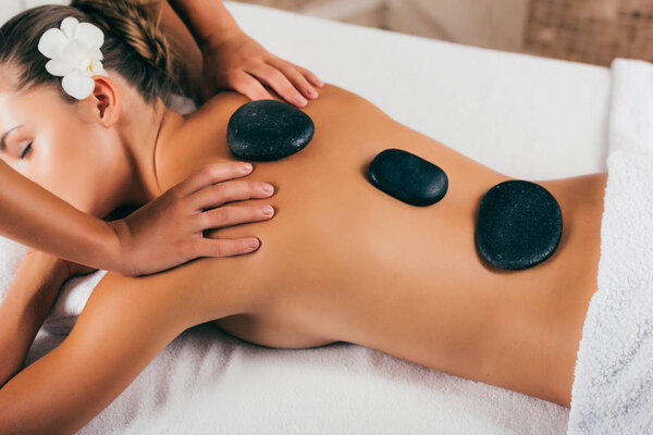 Beautiful young woman having stone therapy at spa salon 