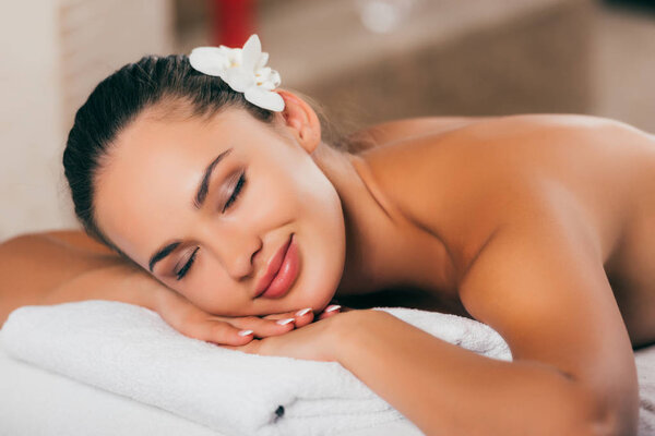 woman with white flower in her hair resting at spa salon 