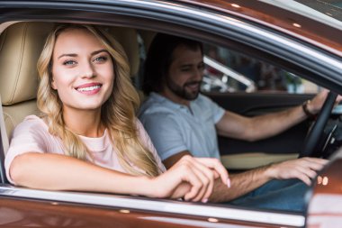 portrait of happy couple in new car at dealership salon clipart