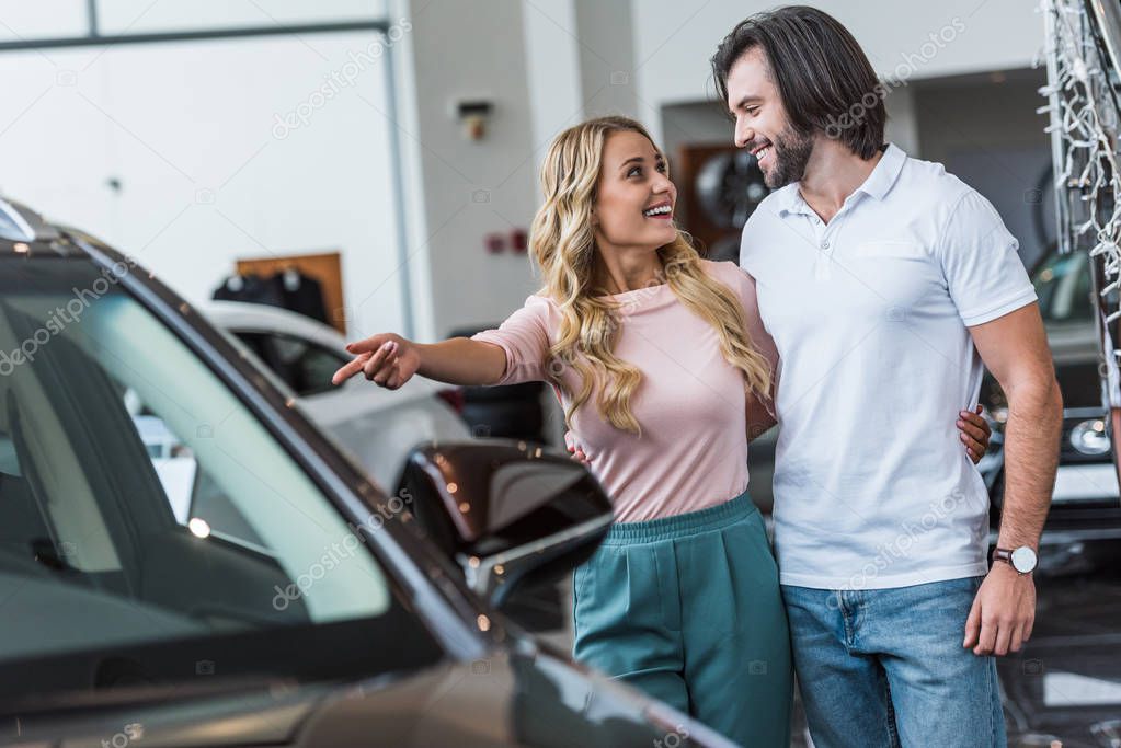 young couple choosing automobile at dealership salon