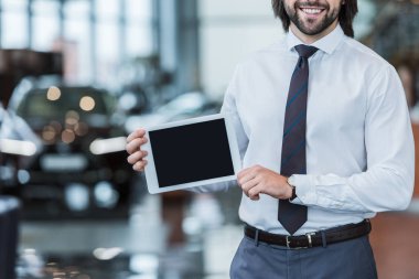 kısmi erkek satıcı formal giyim gösteren tablet ile Bayilik salon boş ekran görünümünü
