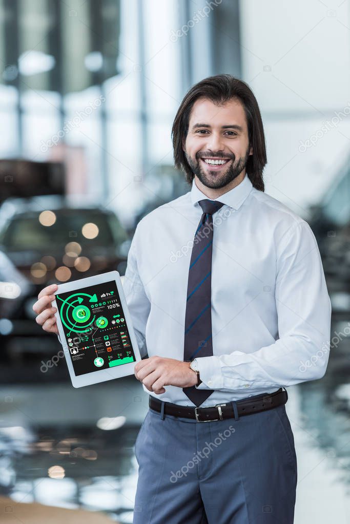 Smiling dealership salon seller in formal wear showing tablet with infographic in hands