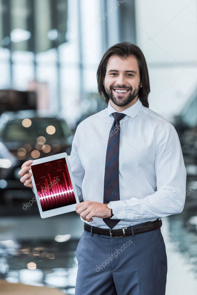 Smiling dealership salon seller in formal wear showing tablet with infographic in hands