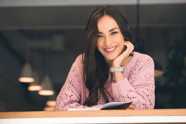 mutlu genç kadın kitap kafede masada oturuyordu