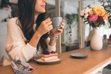 Pasta Cafe ile masada oturmuş kahve fincanı ile kadının resim kırpılmış