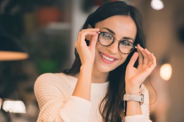 portrait of happy attractive woman taking off eyeglasses in cafe 