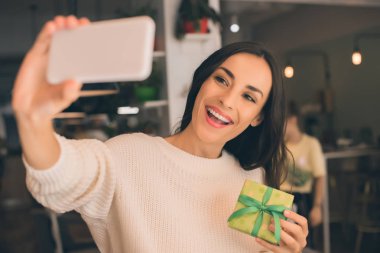 Selfie hediye kutusu Smartphone ile kafede alarak gülümseyen genç kadın