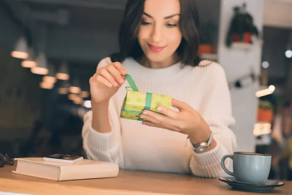 Beautiful Young Woman Untying Gift Box Table Smartphone Coffee Cup — Stock Photo, Image