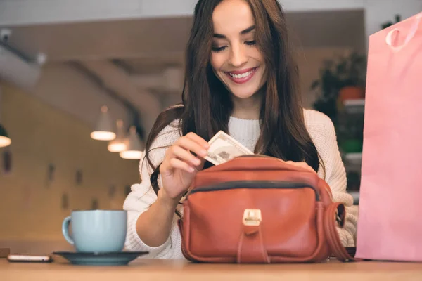 Sorrindo Mulher Retirando Dinheiro Saco Mesa Com Xícara Café Café — Fotografia de Stock