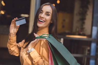 moda gülümseyen kadın ile alışveriş torbaları kredi kartı City sokak gösteren