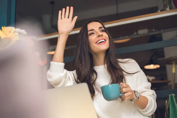 Felice Donna Freelance Con Tazza Caffè Agitando Mano Tavola Con — Foto Stock