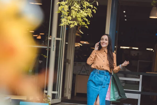 Selectieve Aandacht Van Lachende Vrouwelijke Shopper Met Boodschappentassen Praten Smartphone — Gratis stockfoto