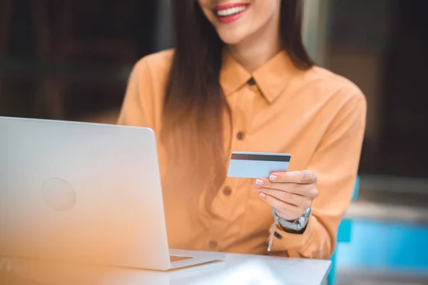 带信用卡的时尚女性的部分视图在城市街道咖啡馆的桌上 在笔记本电脑上进行网上购物 — 图库照片