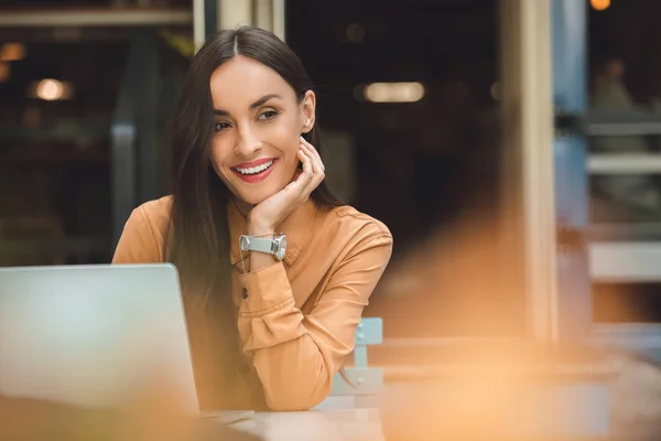 都市通りのカフェでノート パソコンとテーブルを離れて見て若い女性フリーランサーを笑顔 — ストック写真