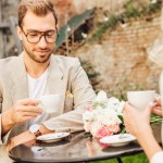 Beskuren bild av par i höst outfit sitter vid bord i café