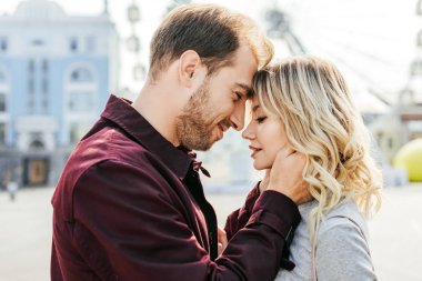 side view of couple in autumn outfit touching with foreheads in city clipart