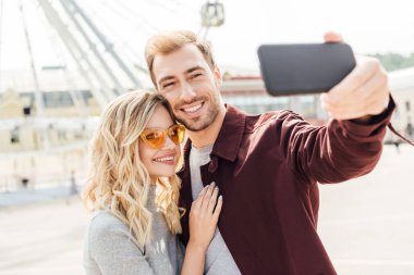 Sonbahar kıyafeti selfie smartphone ile şehirde alarak gülümseyen çift