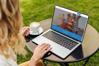 kırpılmış görüntü yüklü couchsurfing sayfa bahçe tablo ile dizüstü bilgisayar kullanan kadın