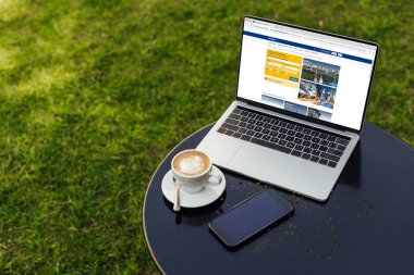 laptop yüklü rezervasyon sayfası, fincan kahve ve smartphone ile Bahçe tabloda boş ekran ile