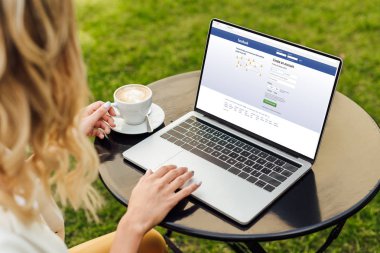 kırpılmış görüntü yüklü facebook sayfa bahçe tablo ile dizüstü bilgisayar kullanan kadın