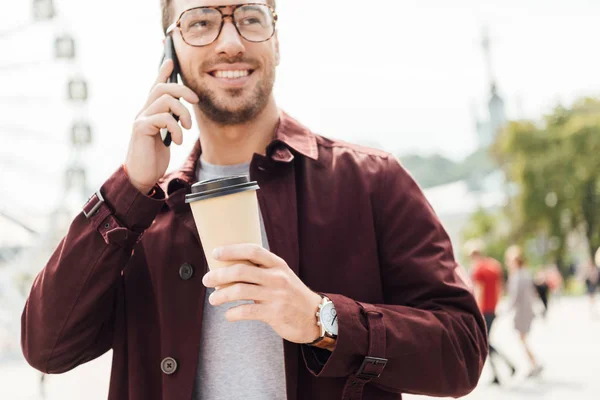 Uśmiechnięty Mężczyzna Jesienny Strój Gospodarstwa Kawę Iść Rozmawiać Przez Smartfon — Darmowe zdjęcie stockowe