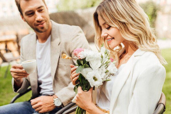 attractive girlfriend sniffing bouquet of roses in cafe