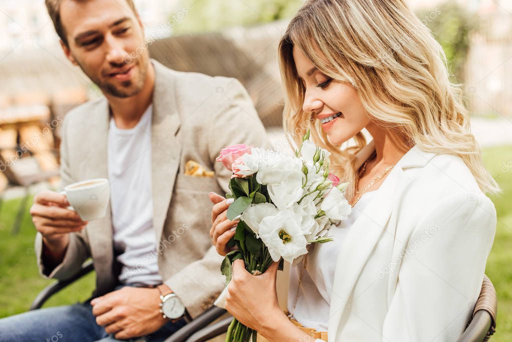 attractive girlfriend sniffing bouquet of roses in cafe