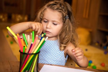 adorable kid choosing colored felt tip pen for drawing in kindergarten clipart