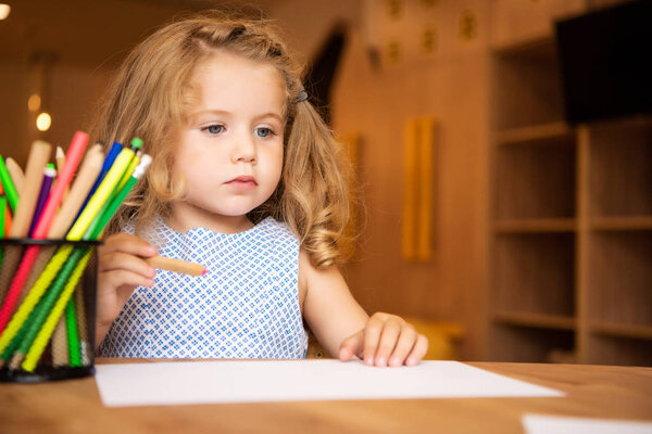 очаровательный ребенок держит войлочную ручку для рисования в детском саду, держатель для ручек с войлочными наконечниками на столе
