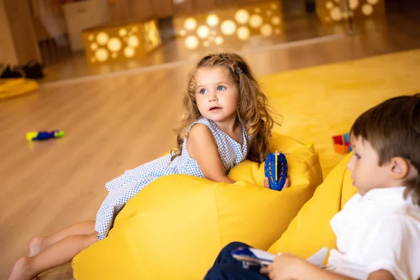 Crianças Adoráveis Com Brinquedos Deitados Cadeiras Saco Feijão Amarelo Jardim — Fotografia de Stock