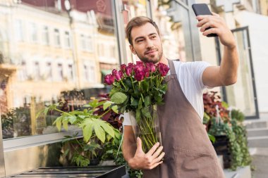 kavanoz ve alma selfie ile smartphone içinde gül çiçek dükkan yakın tutarak yakışıklı çiçekçi