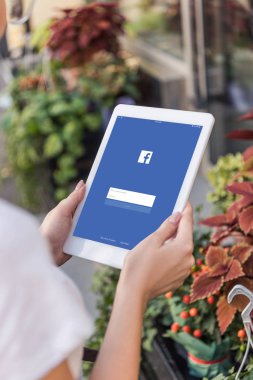 Çiçekçi çiçekçi dükkanı yakınındaki yüklü facebook sayfası ile tablet kullanarak kırpılmış görüntü