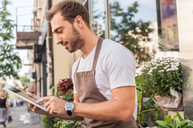 yakışıklı çiçekçi çiçekçi dükkanı tablet kullanarak yan görünüm