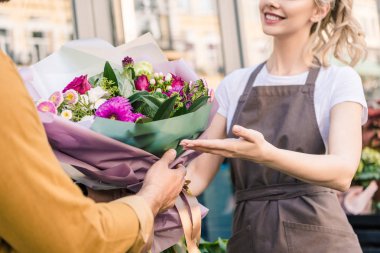 cropped image of florist giving beautiful bouquet of chrysanthemums to customer near flower shop