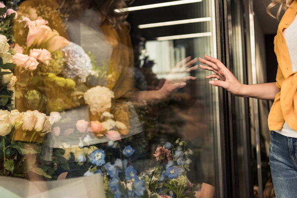 cropped image of girl touching showcase of flower shop