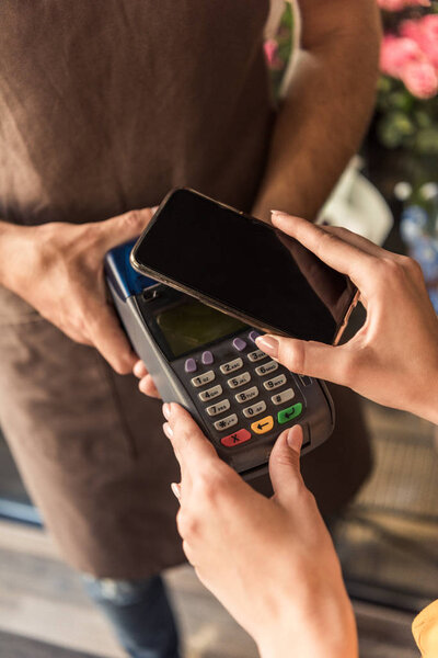 cropped image of customer making contactless payment with smartphone at flower shop