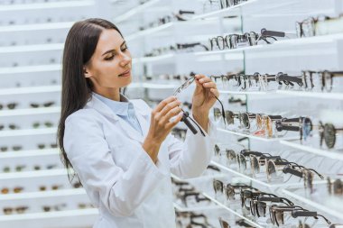 güzel optometrist gözlük gözlük dükkanda raflar yakınındaki bakarak