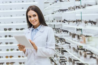 Gülümseyen optometrist oftalmik salonu, seçici odak içinde işte dijital tablet kullanma