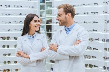 Doktorlar gözlük ile göze ait dükkanda çapraz silah ile poz gülümseyen profesyonel