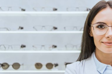 attractive female optometrist in eyeglasses standing in optica clipart