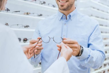 kadın göz göze ait dükkanda genç adam gözlük vererek resim kırpılmış