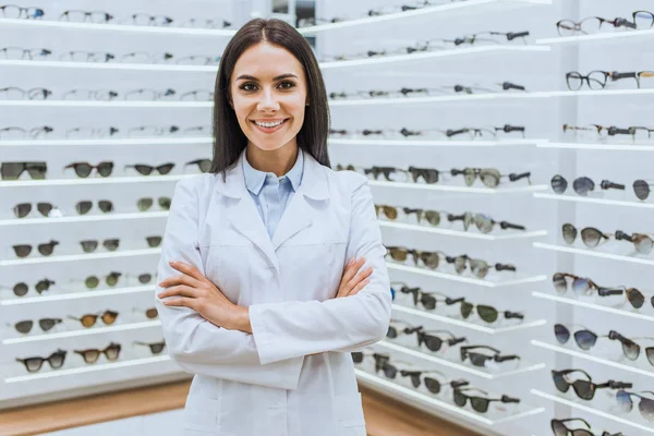 Profissional Optometrista Sorridente Posando Com Braços Cruzados Perto Prateleiras Com — Fotografia de Stock
