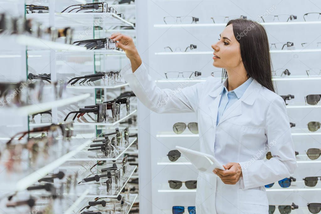 hermosa óptica profesional con tableta digital mirando las gafas en los