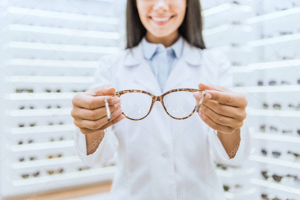 cropped view of professional optometrist holding eyeglasses