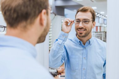 kısmi gözlük seçme ve optica aynaya bakarak adam genç gülümseyen adam görünümünü 
