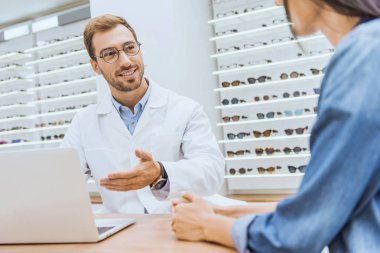 o el ile dizüstü ekran optik işaret ederken erkek göz yakınındaki duran kadın kısmi görünümünü 