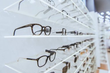 selective focus of white shelves with stylish glasses in ophthalmology clipart