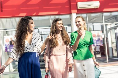 gülümseyen güzel kızlarla konuşuyor ve alışveriş merkezinde yürüyen kağıt torba 