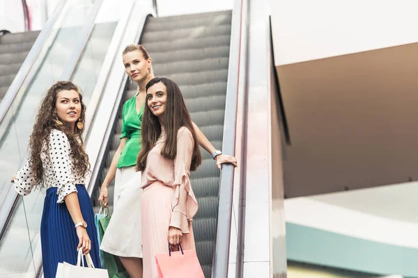 美丽的微笑时尚的年轻妇女举行购物袋在自动扶梯上 — 图库照片